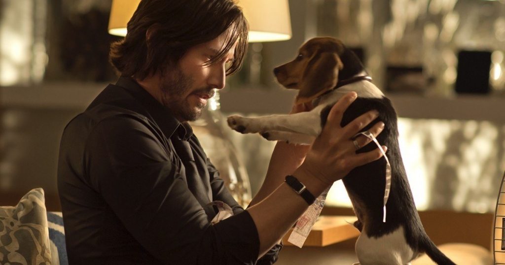 John Wick sosteniendo a su perro de raza Beagle